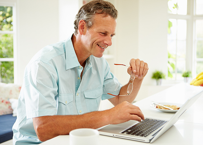Man sitting at kitchen counter browsing the web on laptop